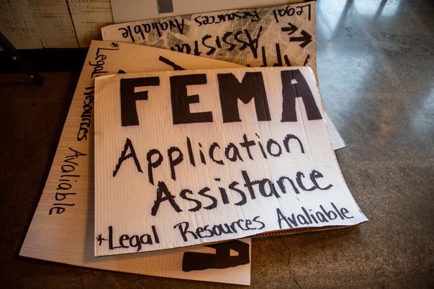 Handwritten signs advertise free assistance with FEMA applications after the July 2022 floods.