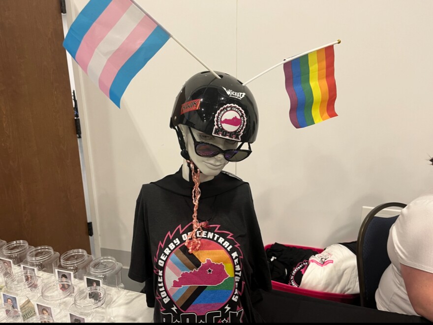 A mannequin at the ROCK merch table is outfitted with gay and transgender pride flags.