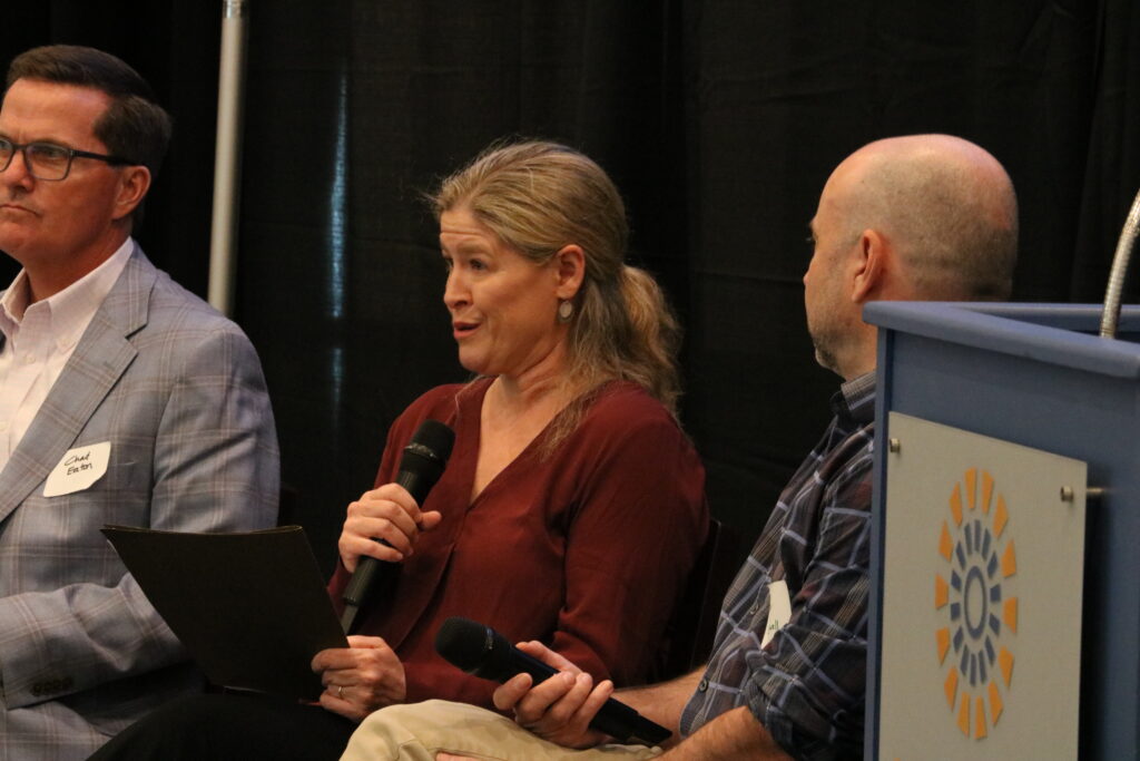 Wilmes speaks into a microphone. 