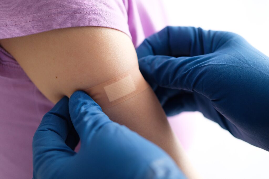 A gloved health care professional applies a patch or adhesive bandage after vaccination or drug injection. (Getty Images)