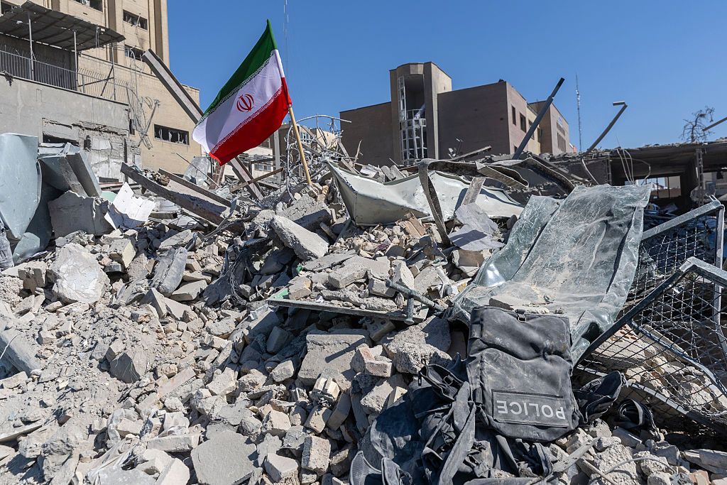 An Iranian flag is planted in the rubble of a police station, damaged in airstrikes on March 3, 2026, in Tehran, Iran. The United States and Israel have continued the joint attack on Iran that began Feb. 28. (Photo by Majid Saeedi/Getty Images)