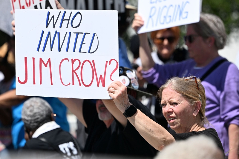 Carsie Evans of Anniston, Alabama holds a sign saying “Who Invited Jim Crow?” outside the Alabama Statehouse on May 4, 2026. The Alabama Legislature began a special session Monday that could result in changes to primary elections and current congressional legislative district lines. (Brian Lyman/Alabama Reflector)