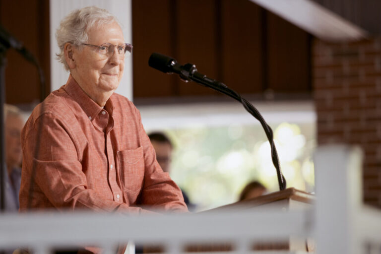 Mitch McConnell smiles while standing at a