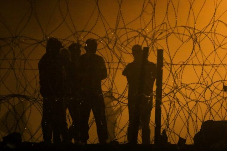 Silhouetted figures stand at
